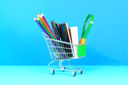 Books pencils pen and magnifying glass on a shopping cart