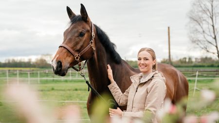 Woman wearing lightweight jacket holding horse