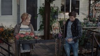 Tye Sheridan standing on a front porch at the bottom of "The Stacks" with his neighbor who is wearing a Police Synchronicity tee shirt