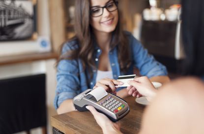 Smiling woman paying for coffee by credit card 