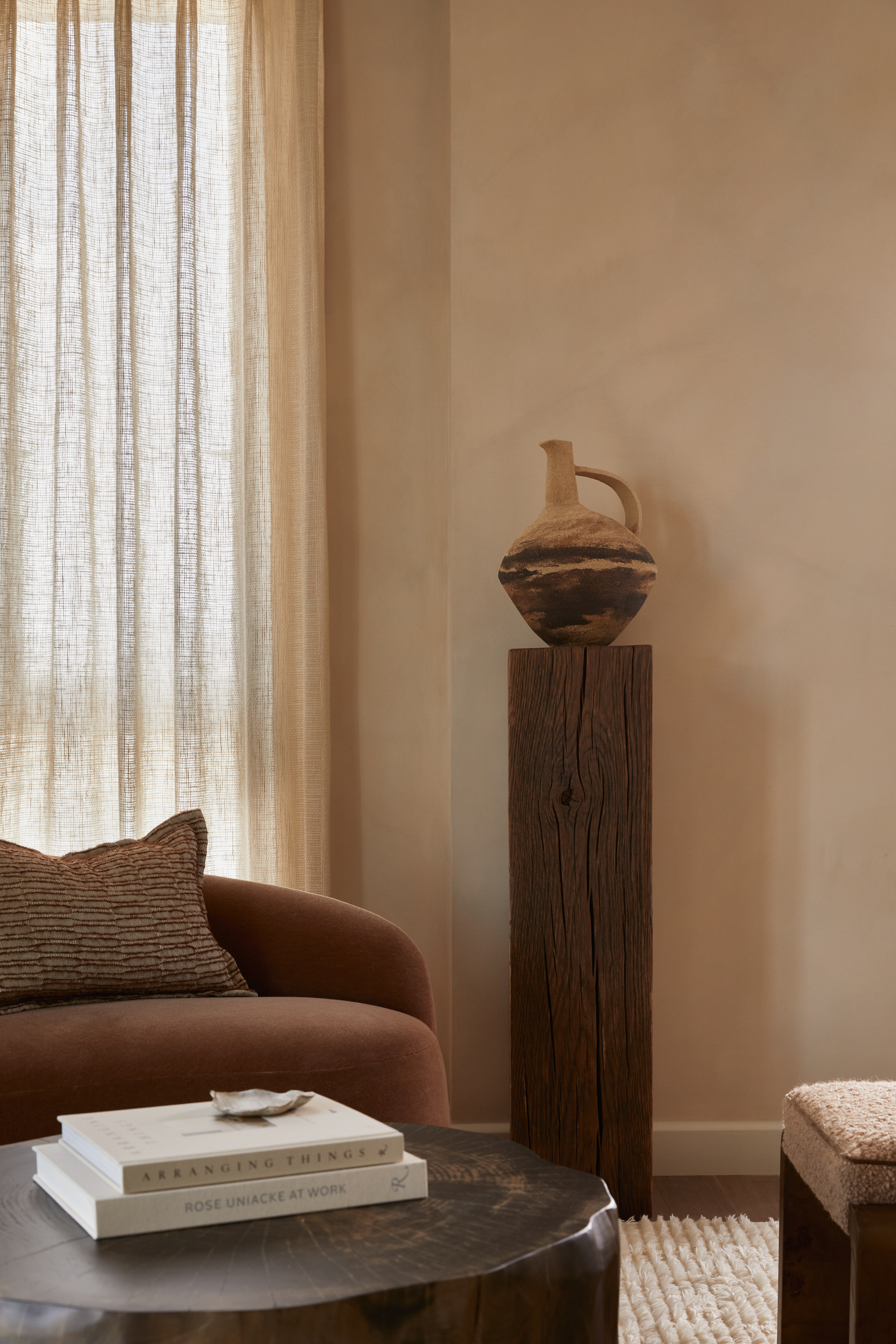 a neutral living room with a ceramic pot displayed on a wooden plinth