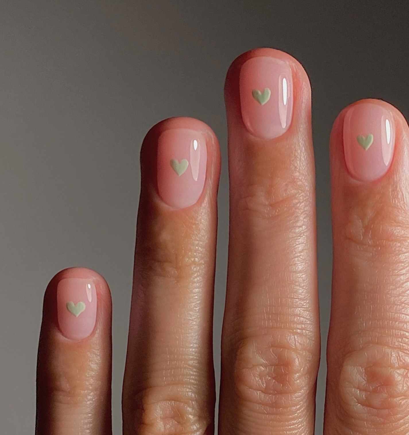 A clear manicure with sage green, heart nail art