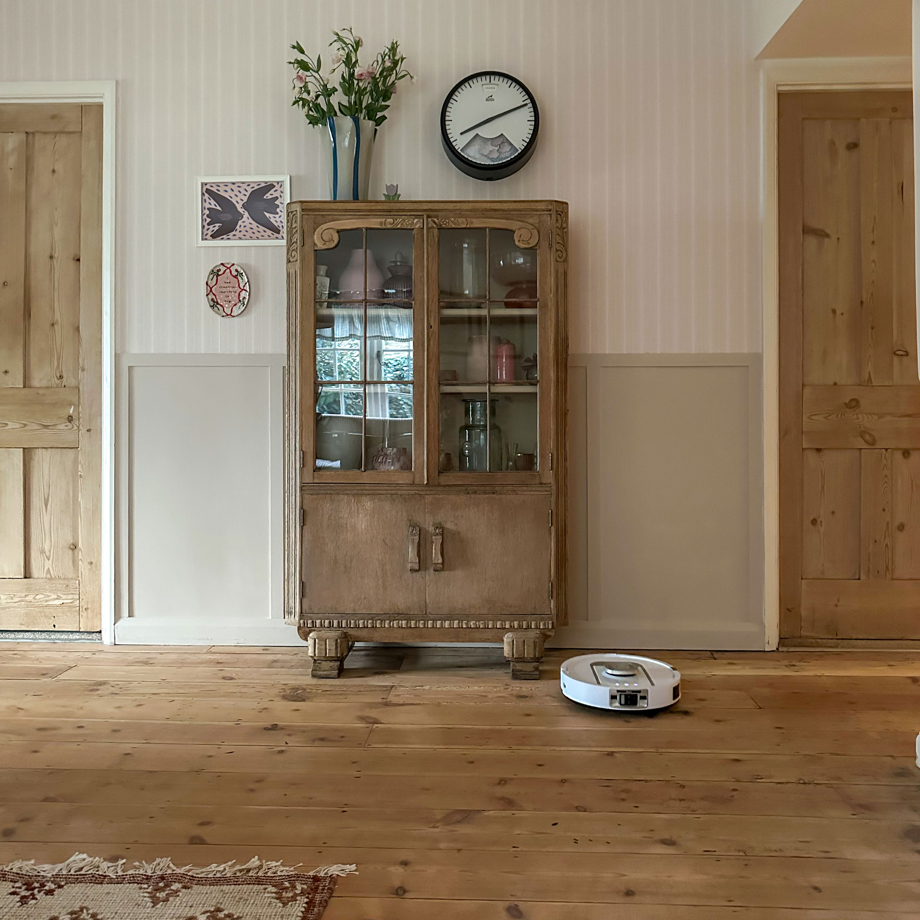 Wooden and glass fronted dresser in living room against pink striped wall