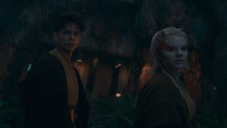 Two Jedi turn around in surprise as they are approached by a dark figure.