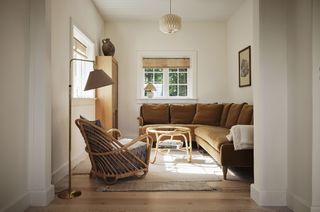small white living room with brown sofa and rattan furniture