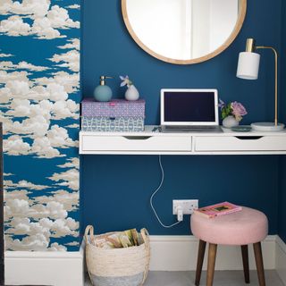 a bedroom with a small area that doubles as a dressing table and home office upholstered stool cloud wallpaper