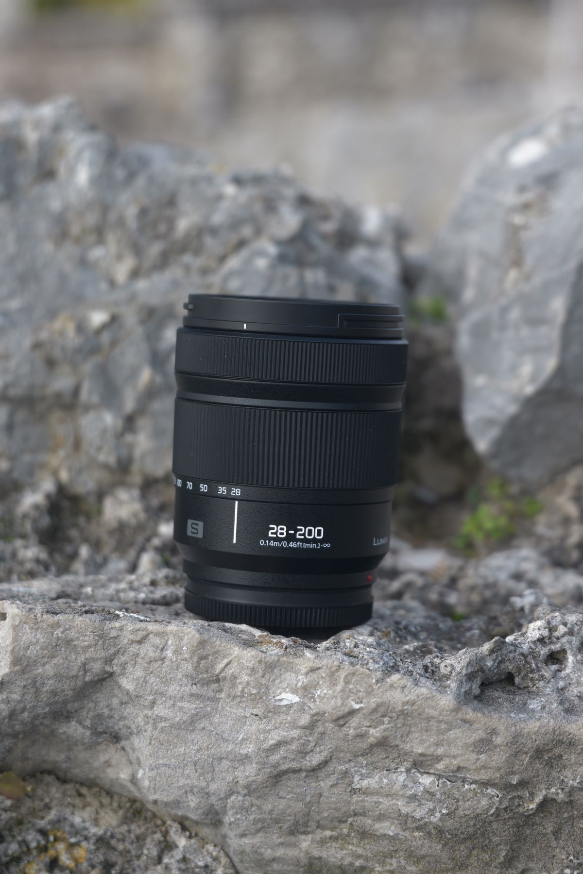 Panasonic Lumix S 28-200mm lens sitting on a rock