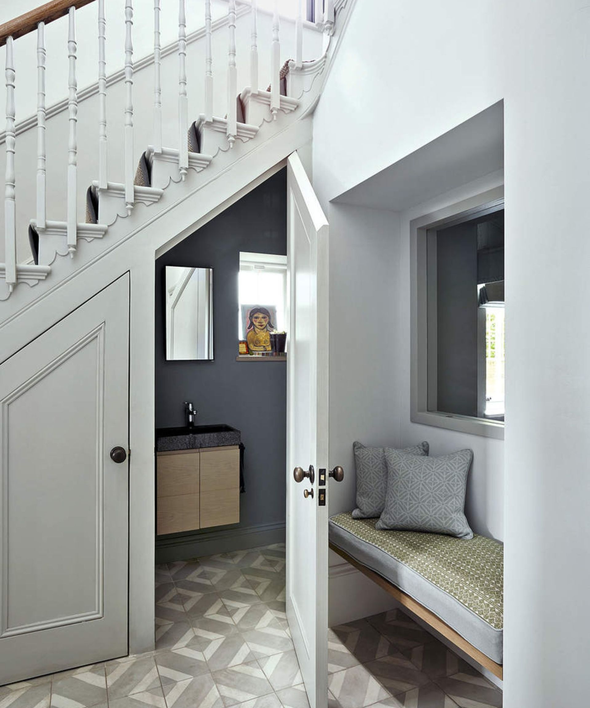 A door ajar to the cupboard under the stairs with white walls.