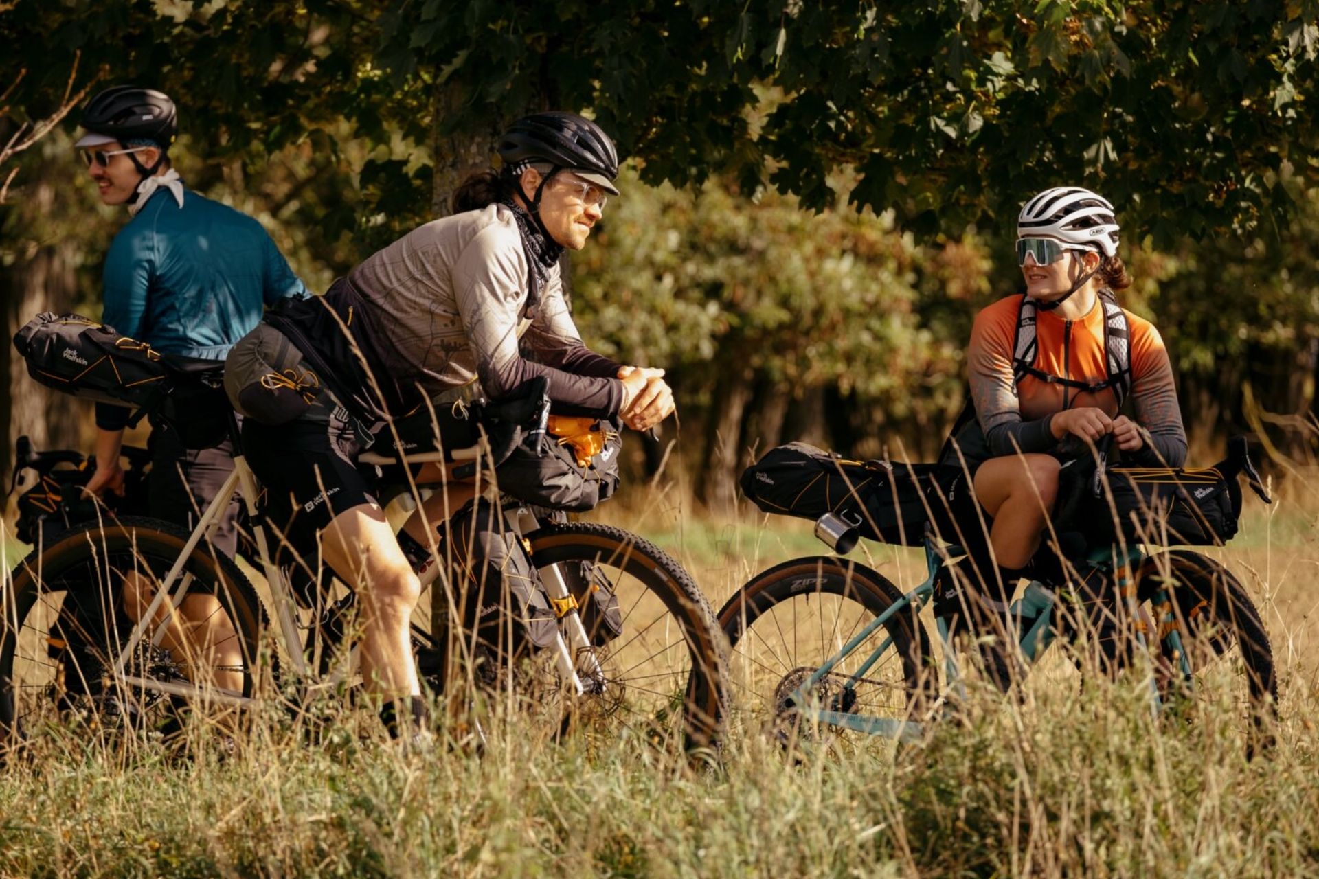 The Jack Wolfskin bikepacking range shown on bikes and on people in a grassy field
