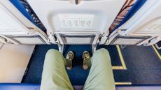 A birdseye view of a person's legs as they look down at their lap on an aeroplane seat