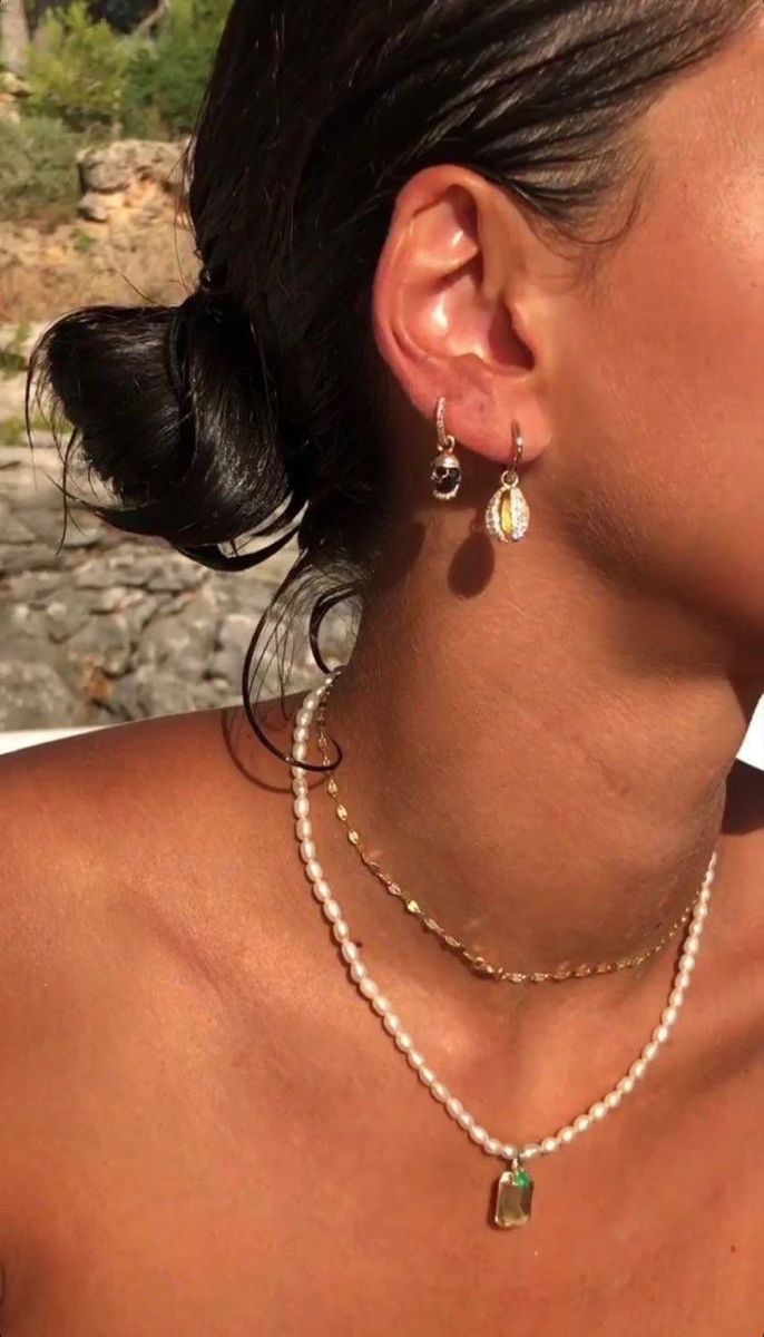 Pearl necklace with emerald pendent layered with a delicate gold choker necklace.