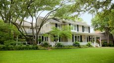 View from the street of an elegant, rambling home with a large front porch and manicured lawn.