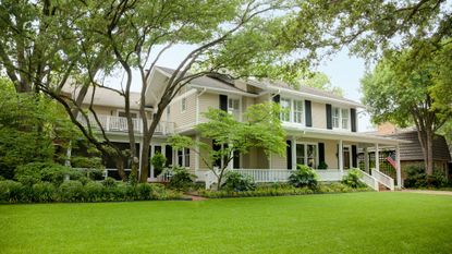 View from the street of an elegant, rambling home with a large front porch and manicured lawn.