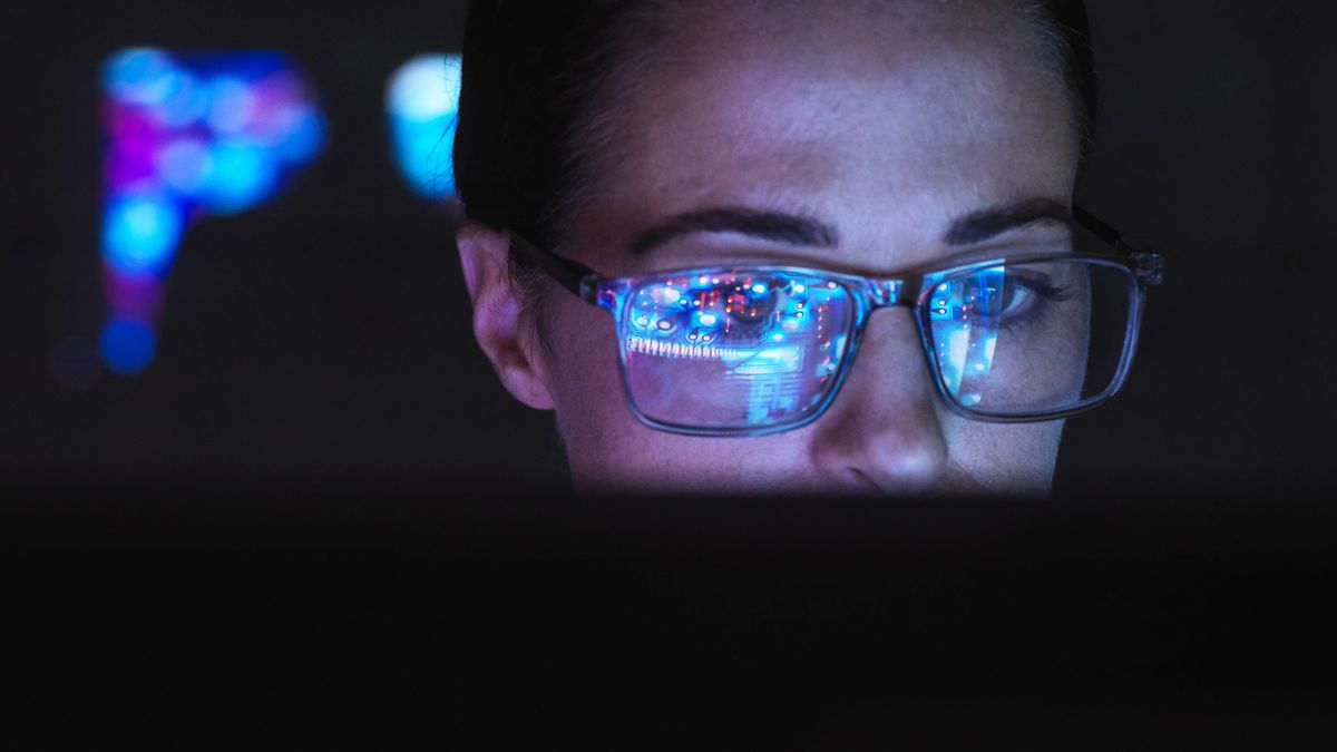 A person wearing glasses with the top two thirds of their face visible looking at a screen with the graphics they&#039;re observing reflected back in their glasses