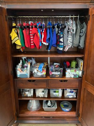 An organized dog clothes closet with hanging items and baskets of supplies