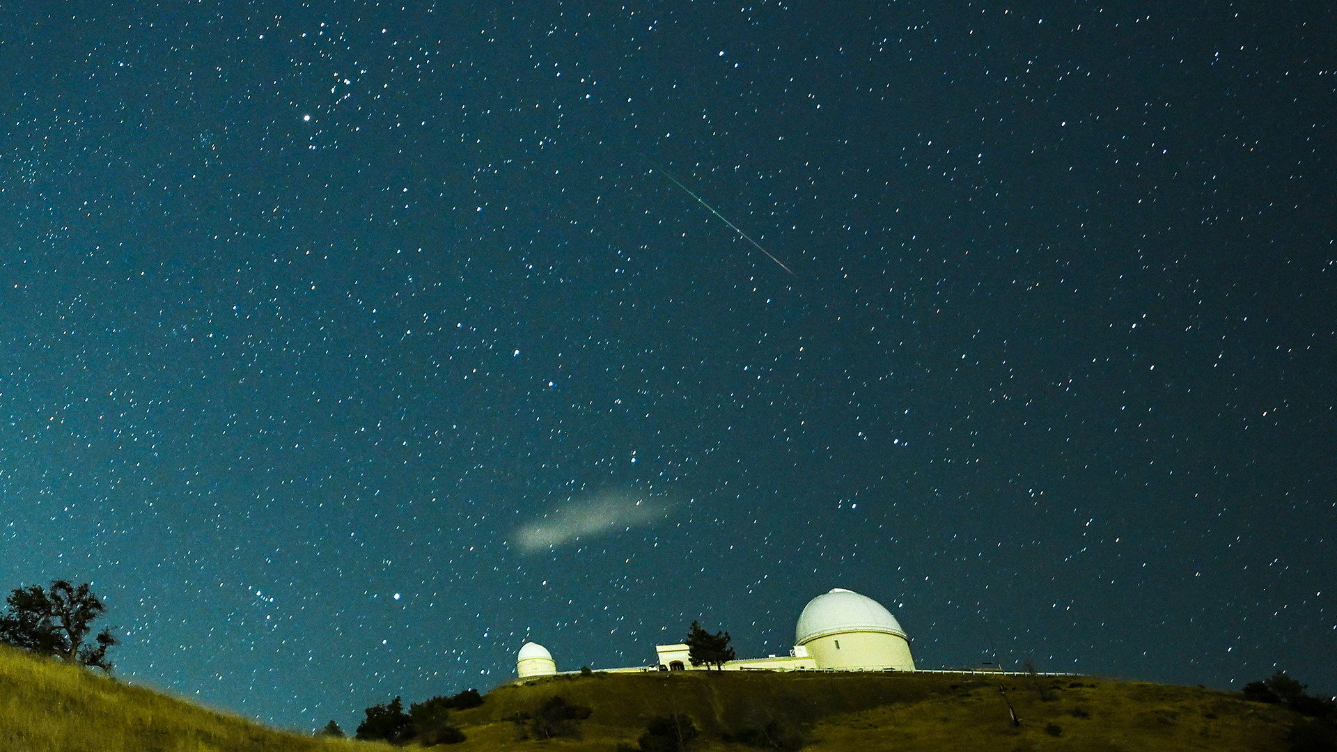 A meteor streaks across the night sky over the Lick Observatory during Perseid meteor shower.