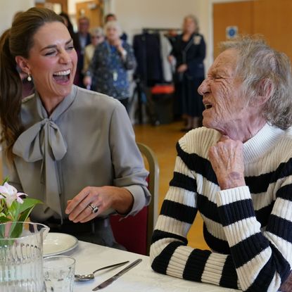 Princess Kate laughing with a woman at a table