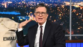 Stephen Colbert sitting next to big bag of emails on The Late Show