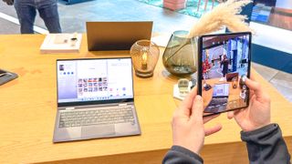An image of a Samsung Galaxy Book 2 Pro 360 and a Galaxy Z Fold 3. The Z Fold 3 is taking a photo of the Galaxy Book 2.