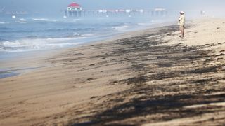A person stands near oil washed up on Huntington State Beach in California on Oct. 3.