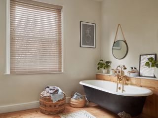 bathroom with wooden flooring and panelling and black bath and wooden blind