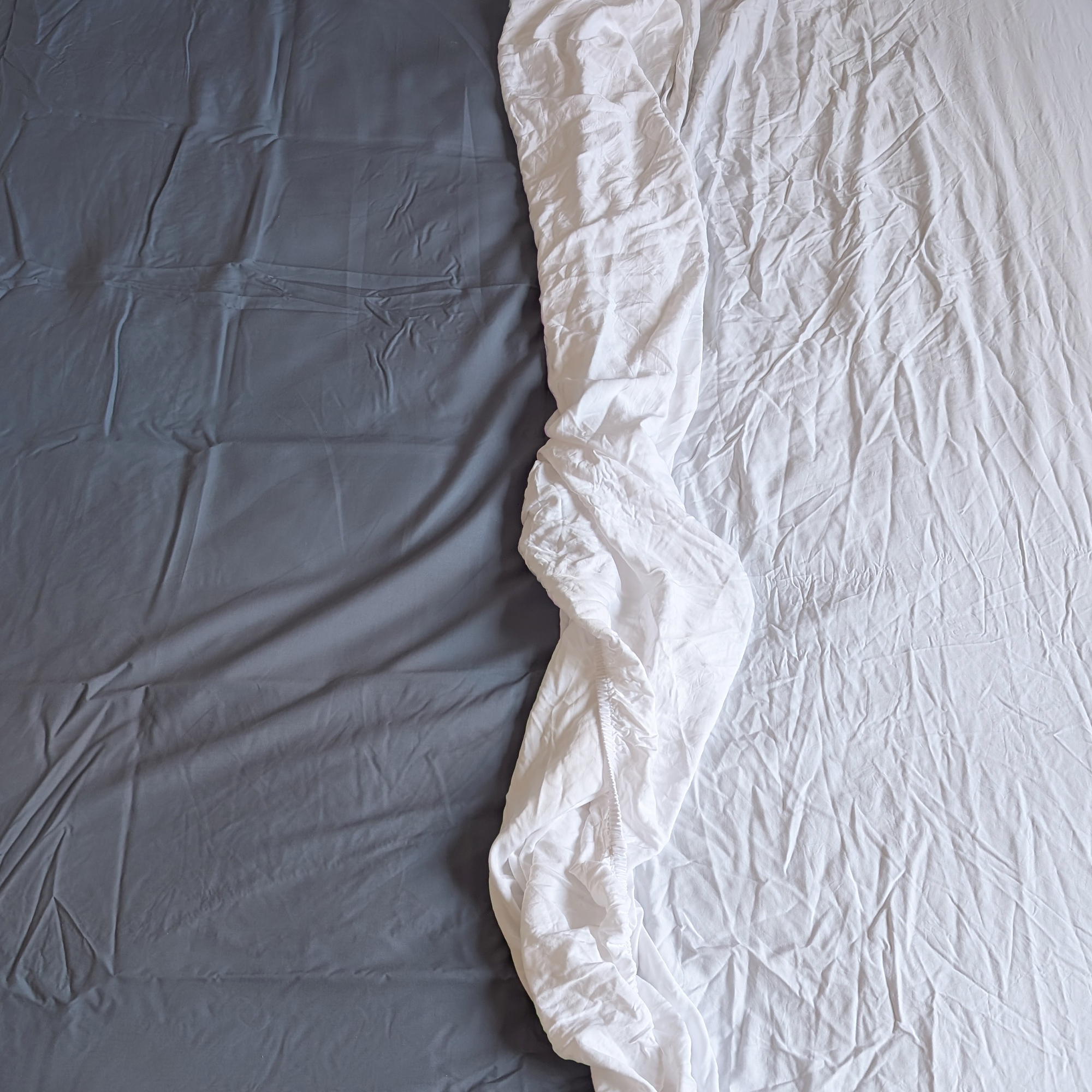 M&amp;amp;S Stay Cool Lyocell Rich Fitted Sheet in blue on a bed with white linen bedding