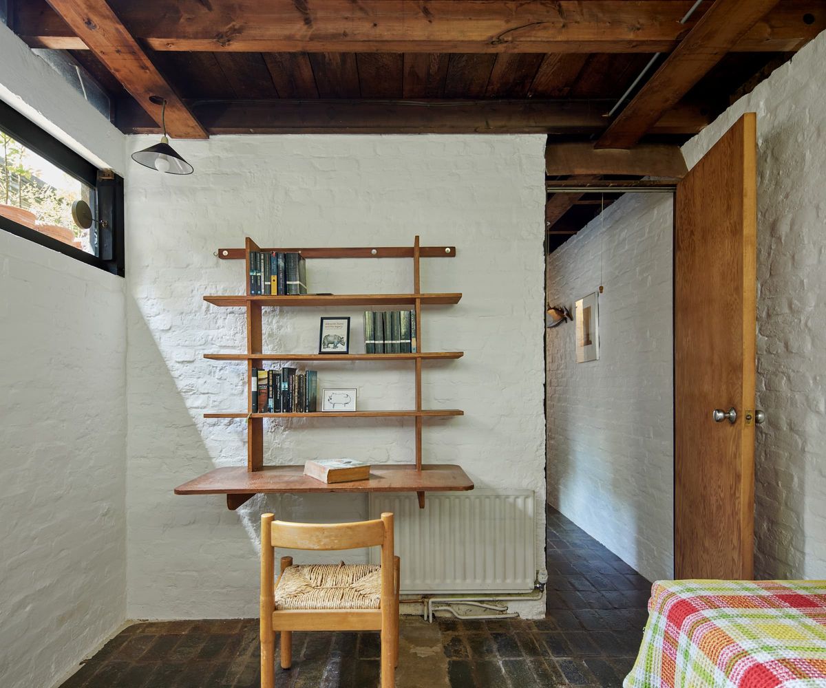 An office space in a bedroom with small wooden chair and wooden shelves