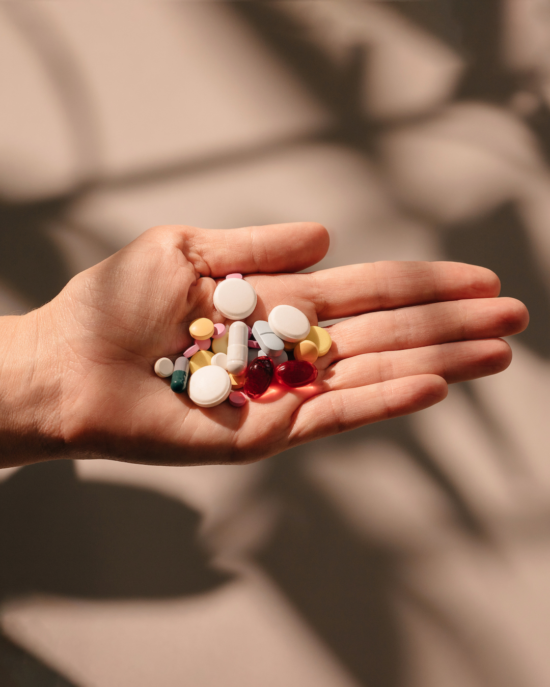 Hand holding skin supplements in different sizes and colours