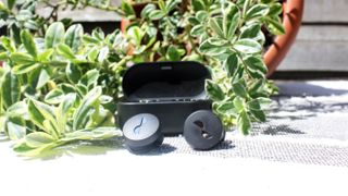 the nuratrue wireless earbuds in front of their charging case