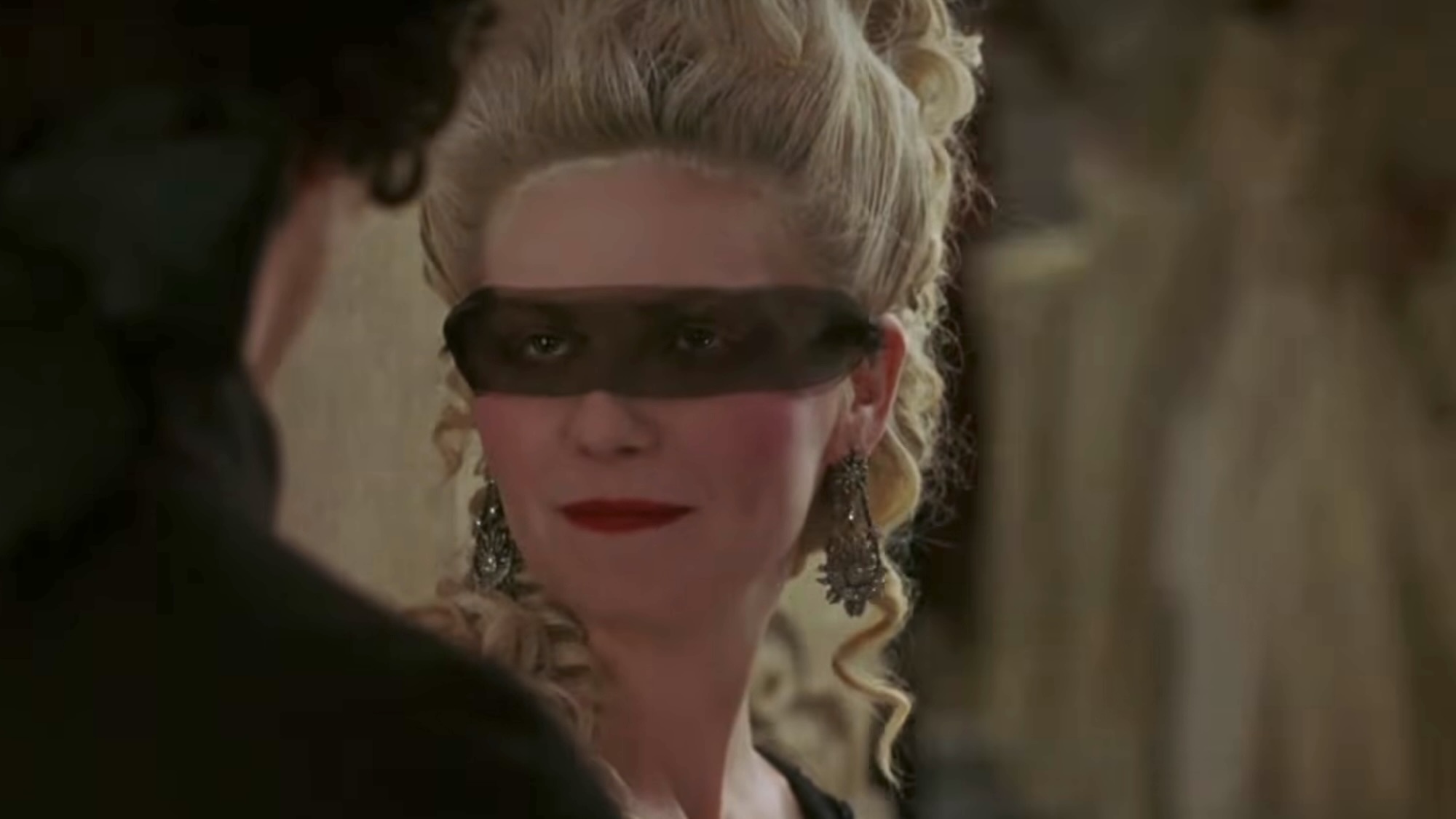 Dunst wearing a mask and smiling during Marie Antoinette's Masquerade scene.