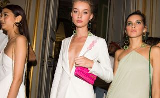 Models wear white blazer with micro pink shoulder bag and light green top