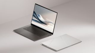 Two of the Asus Zenbook S16, one with lid open and one with lid closed, in front of an abstract gray background