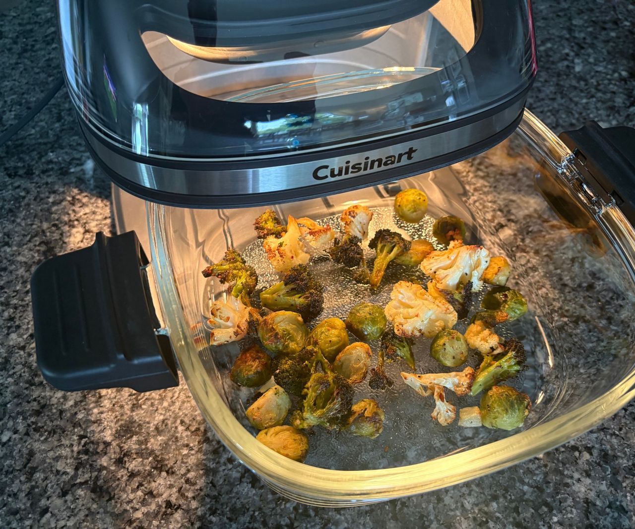 The Cuisinart glass air fryer on a granite countertop with fried vegetables in the pulled out basket.
