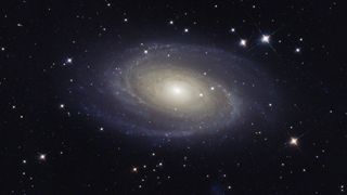 Bode's galaxy hangs in space among a sea of stars, featuring a bright central core and sweeping spiral arms.