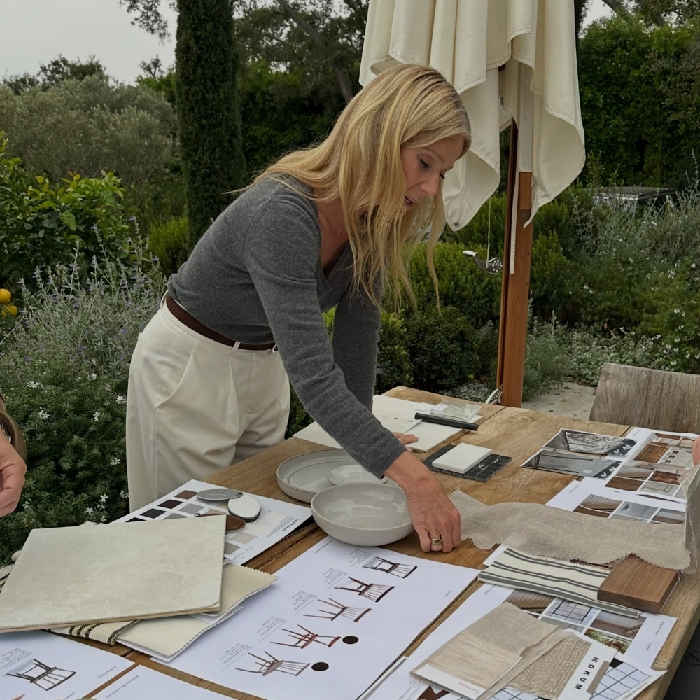 Gwyneth Paltrow wears a grey jumper with white trousers.