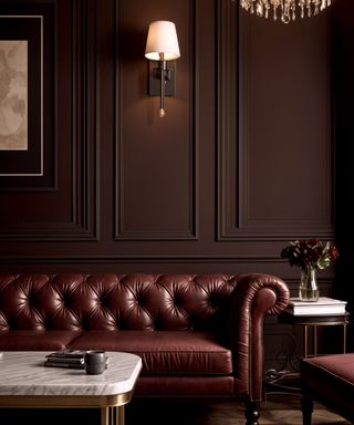 dark and moody living room with brown panelled walls, brown leather traditional sofa and marble coffee table