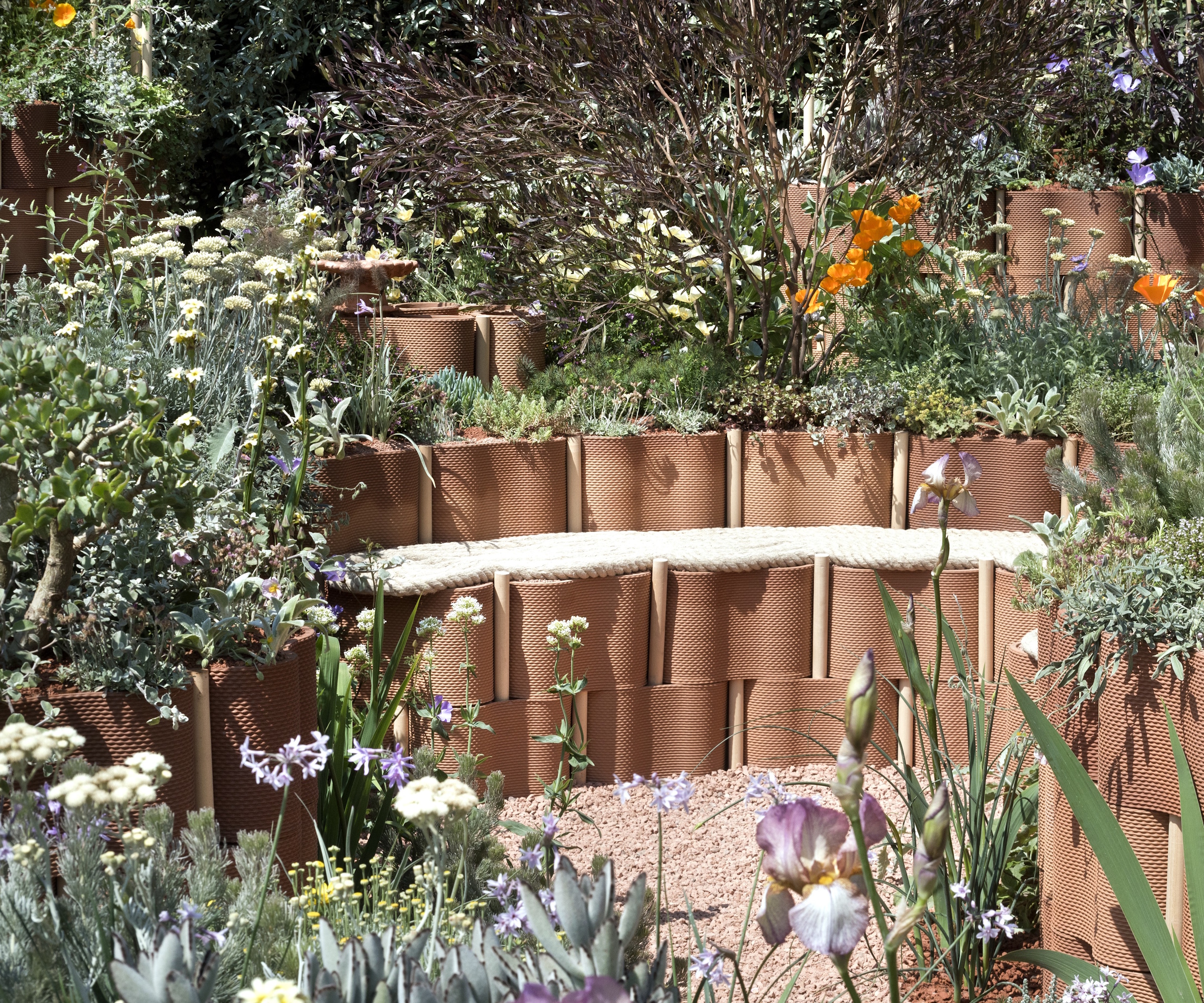 RHS Chelsea Show Garden with terracotta seating and wildflowers