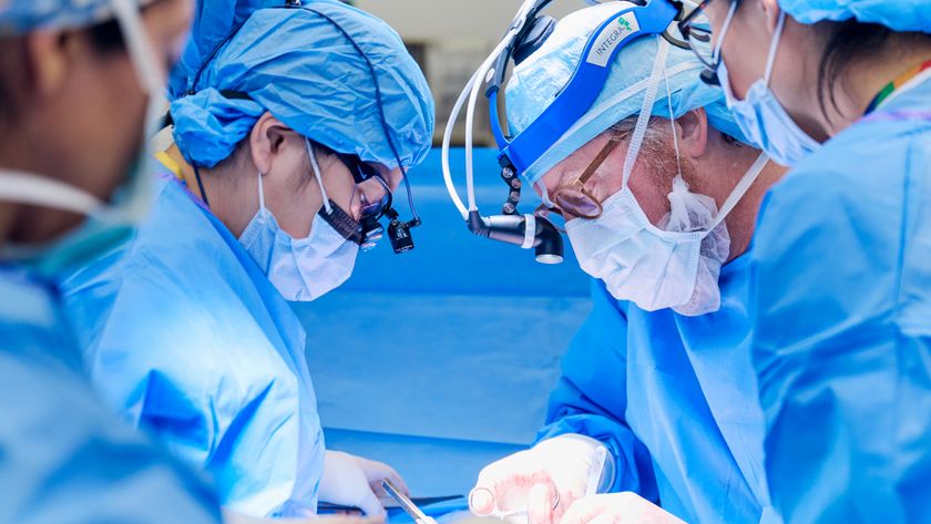 Four doctors looking down during surgery.