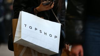 A woman carrying a Topshop shopping bag