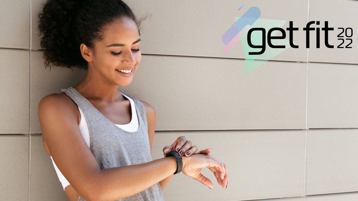 Woman resting against a wall, checking her fitness tracker