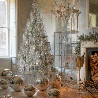 A silver Christmas tree surrounded by oversized silver baubles