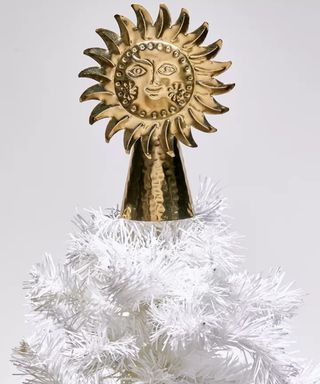 Celestial sun-shaped, brass colored iron Christmas Tree Topper on white artificial Christmas tree