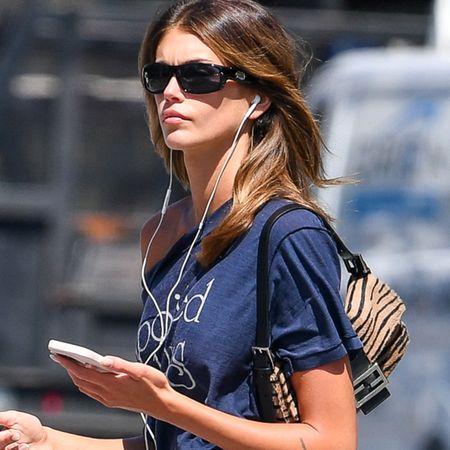 Kaia Gerber is pictured stepping out in New York City. The 24 year old model and actress carried a Fendi tiger print bag and wore a Spoiled Boys T-shirt, black knee-length skirt, and ballet flats.