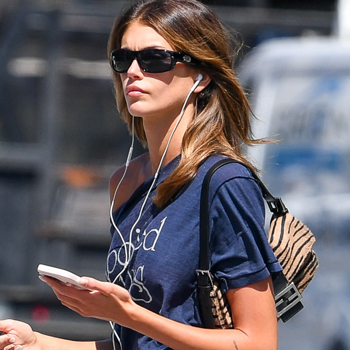 Kaia Gerber is pictured stepping out in New York City. The 24 year old model and actress carried a Fendi tiger print bag and wore a Spoiled Boys T-shirt, black knee-length skirt, and ballet flats.