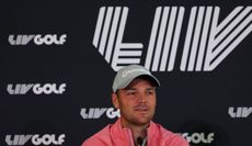 Martin Kaymer in front of a LIV Golf logo 