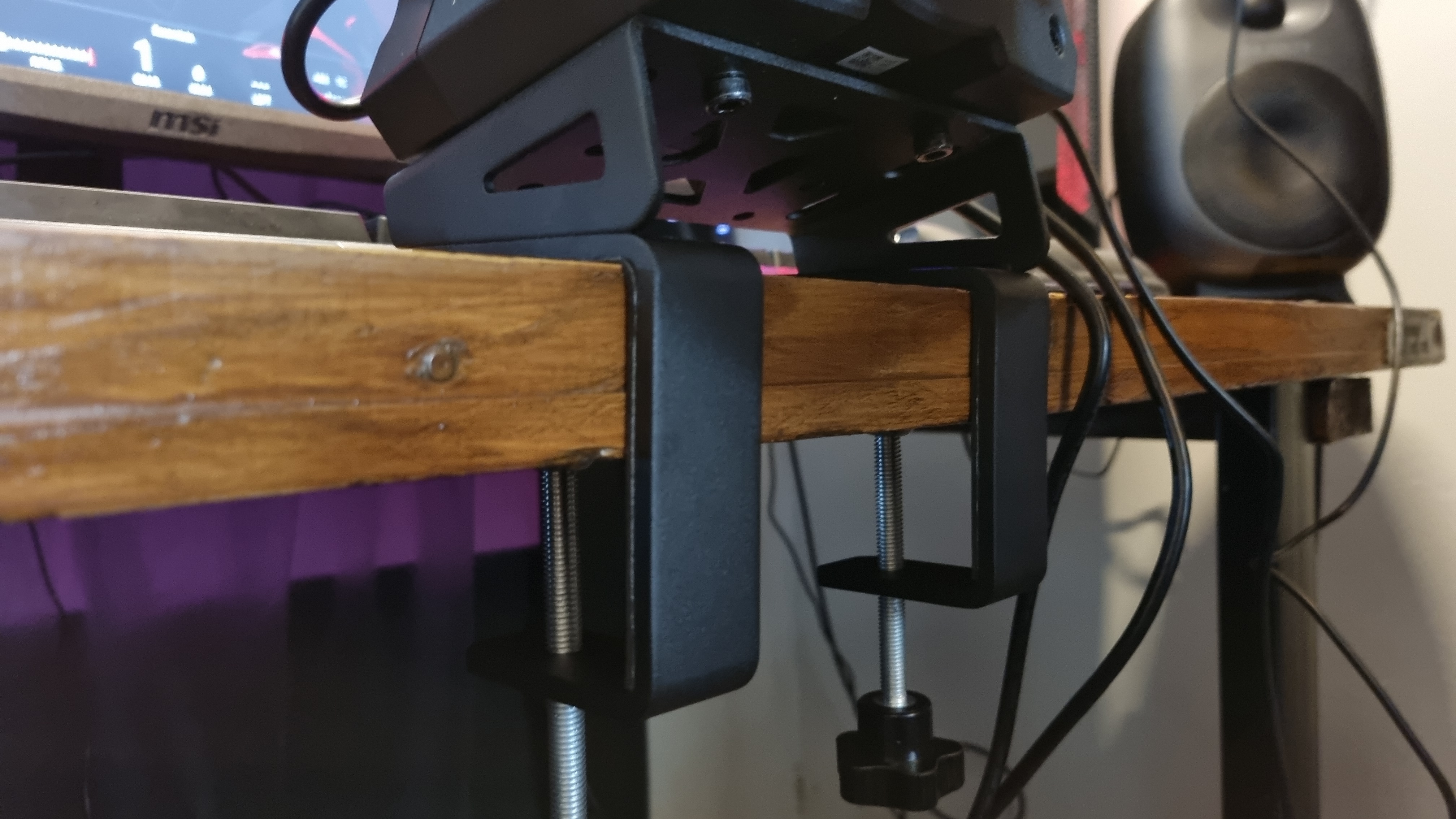 The MOZA R5 desk clamp, mounted to a wooden desk