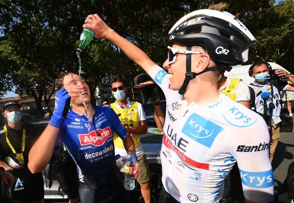 Tadej Pogacar pours a San Pellegrino on stage winner Jasper Philipsen