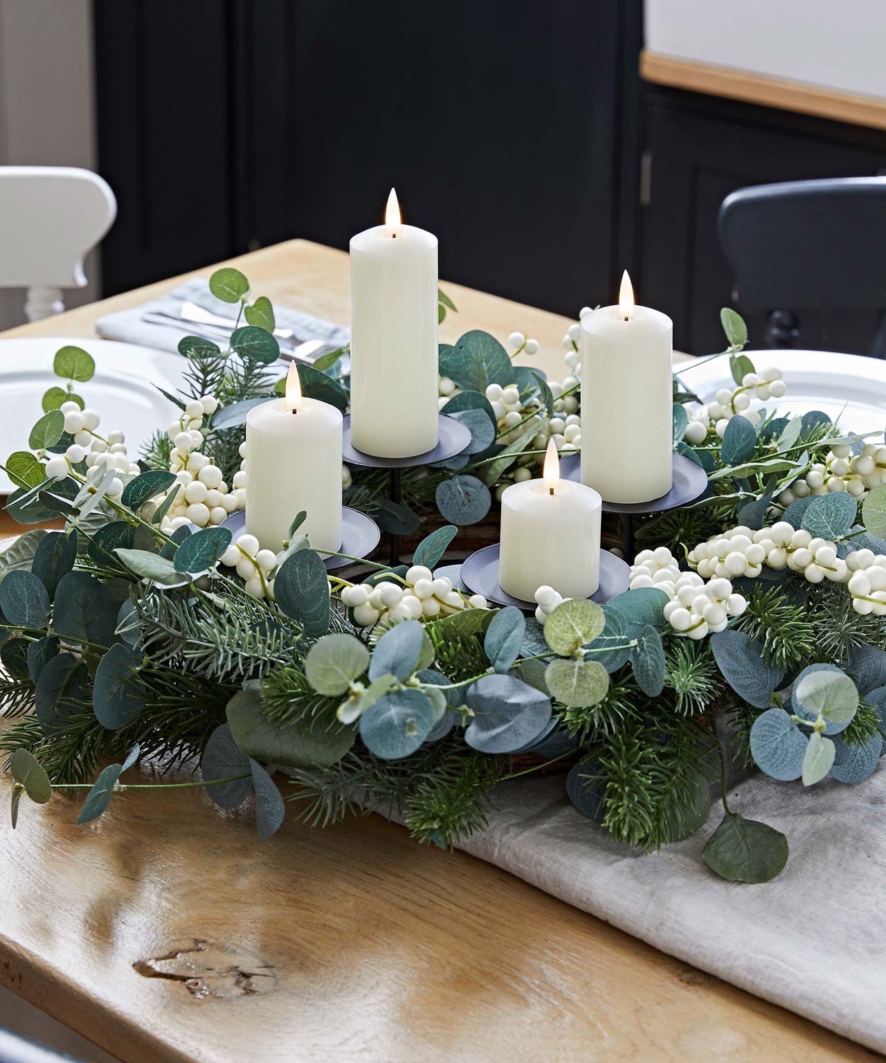 Wreath of eucalyptus and pillar candles on a table