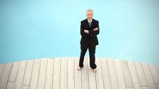 A businessman stands by a pool.