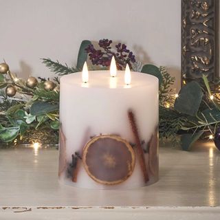 LED winter candle with fruit in the wax on a ledge with a garland to suggest how to style a hallway